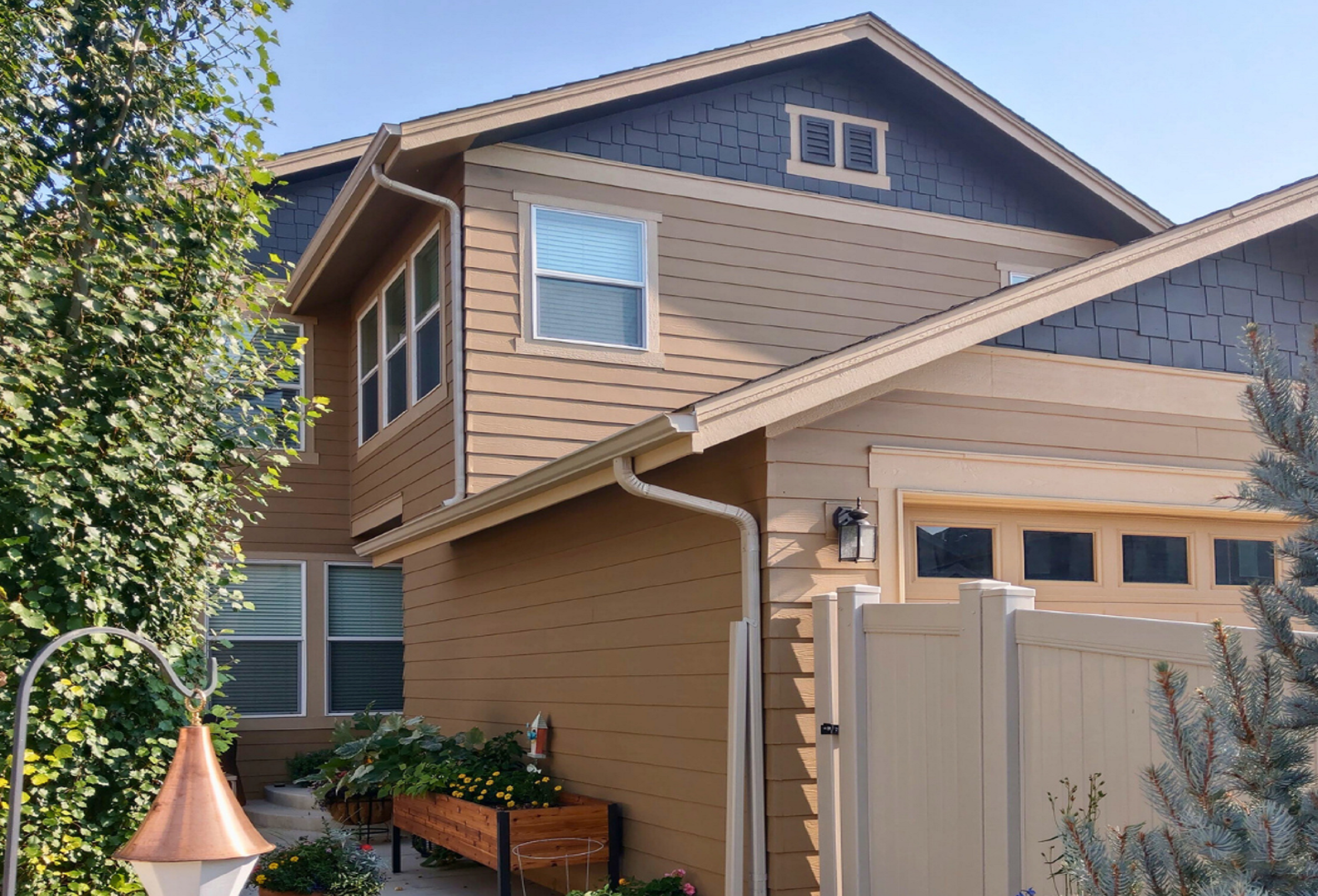 Newly installed white gutters along a two-story Fort Collins home with tan siding and blue-gray shake gable